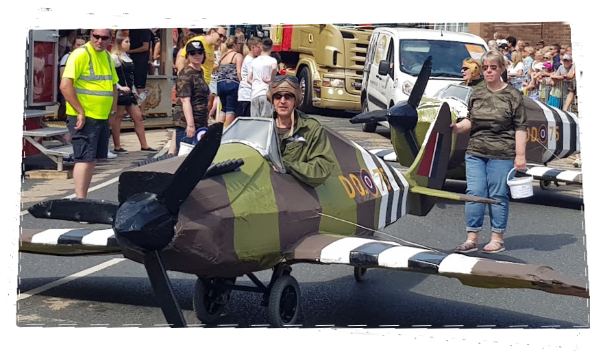 photo of man in a rideable model spitfire aeroplane